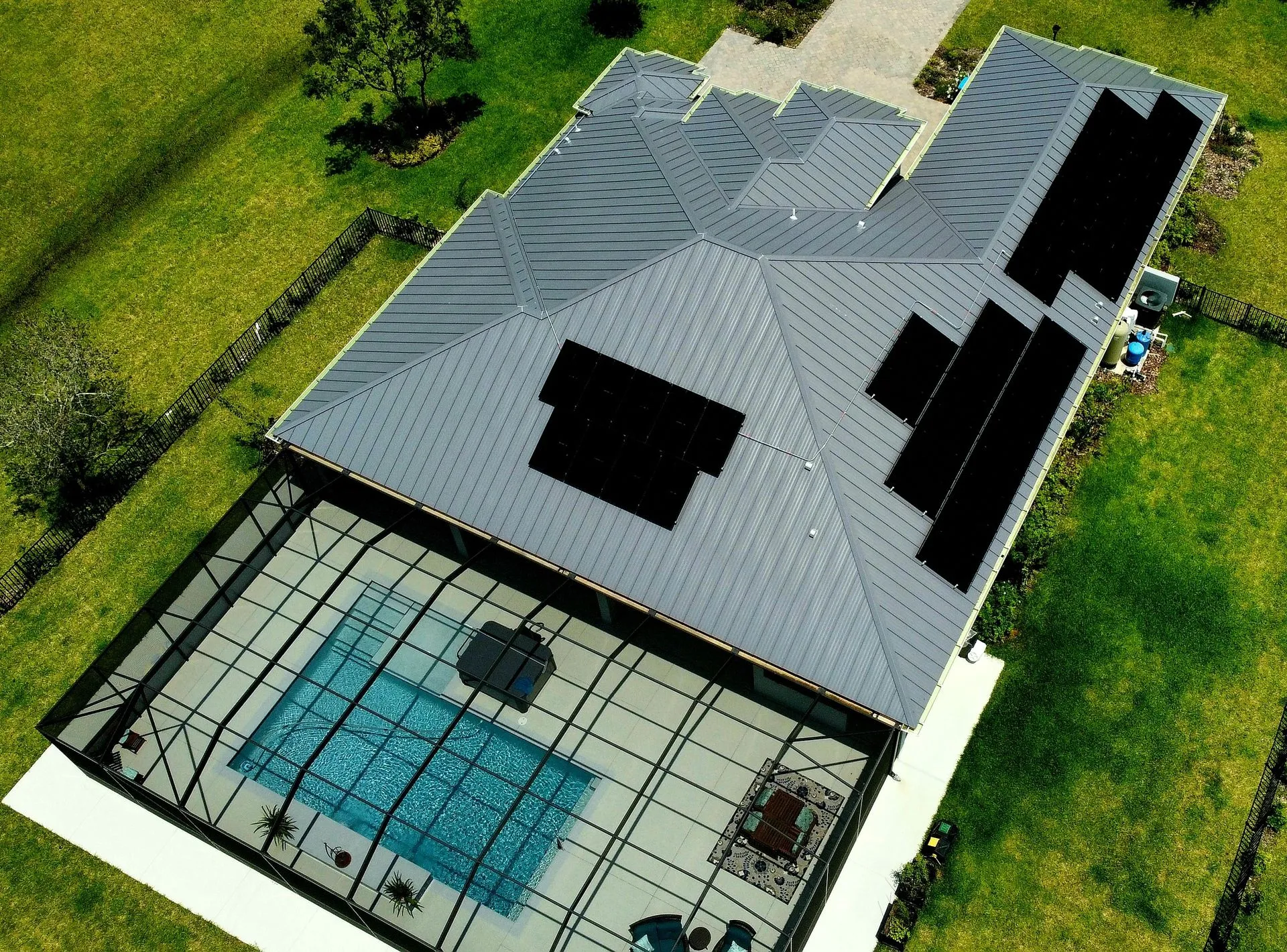 Aerial view of a Florida home with rooftop solar panels and a screened pool